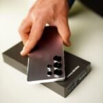 Close-up of hand holding Samsung Galaxy S25 Ultra smartphone with box.