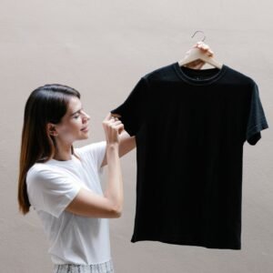 Side view of positive female wearing casual outfit standing with black shirt against gray background